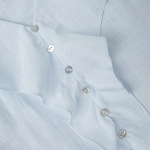 Detail of blue cotton top featuring mother-of-pearl buttons and fine stitching textures