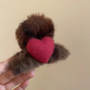 Vue détaillée de la pince à cheveux en peluche marron avec un cœur en feutre de laine rouge