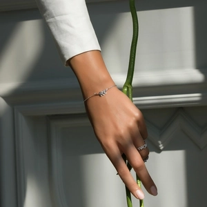 Detailed close-up of 925 sterling silver leaf bracelet and ring set on model's hand