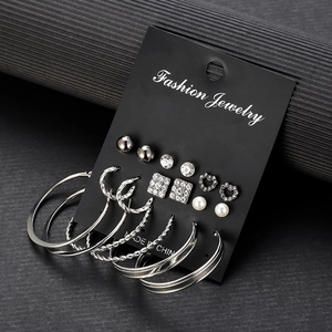 Detail of 9-pair silver earring set featuring pearls, studs, and hoops on a black card