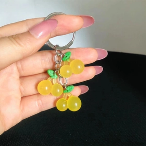 Close-up of translucent yellow cherry key ring with silver chain held by a hand