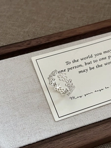 Detailed view of hollow flower silver ring placed on a minimalist gift quote card