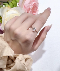Elegant rose gold moissanite ring featuring an emerald cut stone on a model's finger