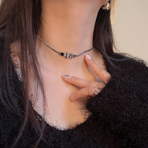 Detail of silver belt buckle choker with smooth snake chain on a female model