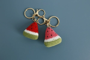 Detailed stitch texture of handmade crochet watermelon charms with gold metal keyrings