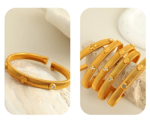 Detail of gold snake-bone textured cuff bracelet with crystal clover and spiral design