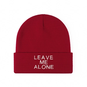Detailed view of white LEAVE ME ALONE embroidery on burgundy knitted beanie