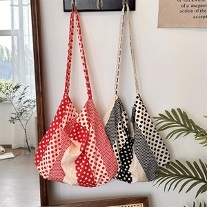 Detailed view of red and black polka dot canvas tote bags hanging in a lifestyle setting