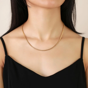 Close-up of elegant gold stainless steel snake chain necklace worn on a model's neck