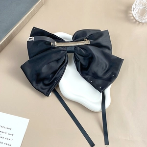 Detailed view of the silver metal spring clip on a large black satin bow hair accessory