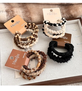 Close-up of elegant coffee-toned plush hair ties with wooden beads on jewelry tray