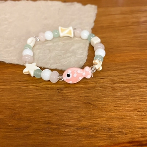 Close-up of a colorful beaded bracelet featuring a pink fish charm and white star beads