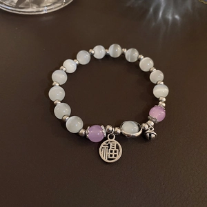 Detail of beaded bracelet with cat eye stones, Fu charm and silver bell on leather