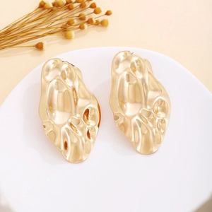 Detail shot of vintage gold flower pearl earrings with textured metal on a white plate