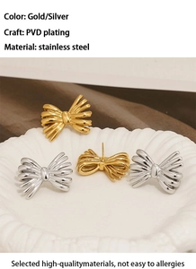 Detailed macro view of gold and silver bow stud earrings on a white ceramic plate
