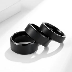 Close-up of three matte black tungsten rings with polished beveled edges on white base