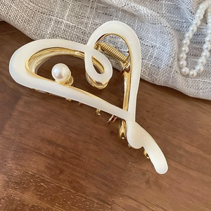 Détail d'une pince à cheveux cœur vintage en émail blanc avec perle élégante