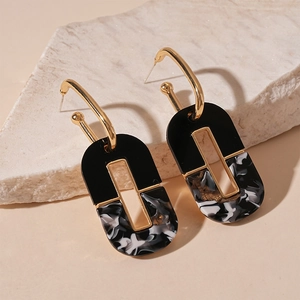 Detail view of geometric acrylic U-shaped drop earrings on a natural stone display