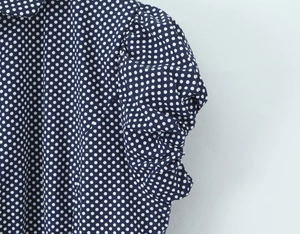 Detail of navy blue blouse showing puffed shoulder seam and white polka dot pattern texture