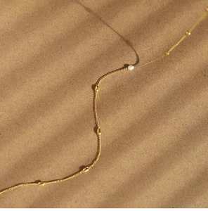 Close-up of 18K gold-plated necklace with elegant white pearls and small gold beads