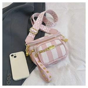 Detail of pink and white striped saddle bag with geometric wide strap and gold hardware