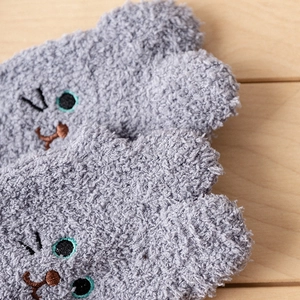 Close-up of grey coral fleece socks with cat embroidery detail on soft plush fabric