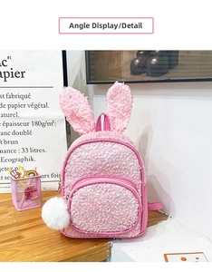 Detail view of pink sequin toddler backpack with bunny ears and white pompom charm