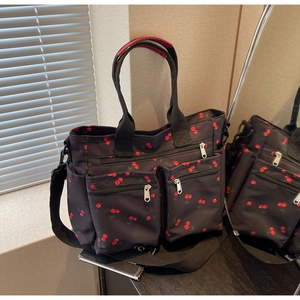 Detail view of printed canvas tote bag with cherry patterns and multi-pocket design