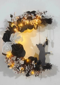 Detail of crescent moon cat wreath with black roses and glowing LED lights for home decor