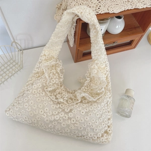 Detailed close-up of cream lace tote bag featuring daisy embroidery and ruffled edges