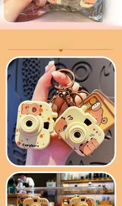 Close-up of camera-shaped capybara charms with lobster clasps and vintage metal rings