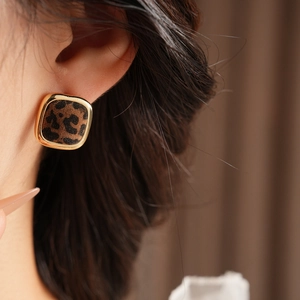 Close-up of leopard print square stud earrings with gold metallic frame on model