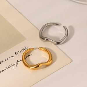 Detailed view of wave pattern rings in gold and silver finish on a warm beige card