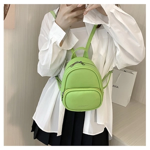 Lifestyle view of the light green mini PU leather backpack worn by a model in a casual outfit