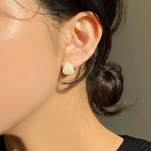 Elegant 925 sterling silver stud earrings with organic cream resin squares on a model