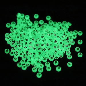 Macro shot of luminous round letter R beads glowing green in the dark for DIY jewelry