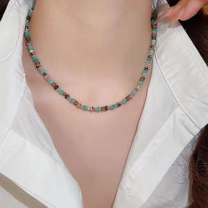 Close-up of a colorful beaded necklace with stainless steel charms on a model
