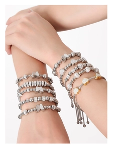 Detail of stacked gold and silver bracelets with charms worn on a model's arm