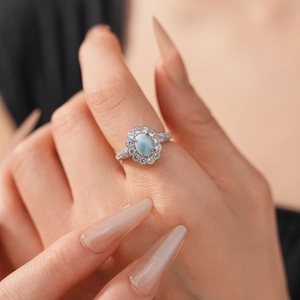 Detail of light blue oval gemstone ring with diamond halo and pavé band on model