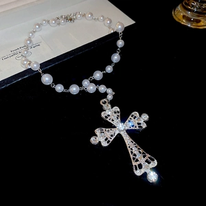 Close-up of sparkling rhinestone hollow cross pendant on a white pearl strand necklace