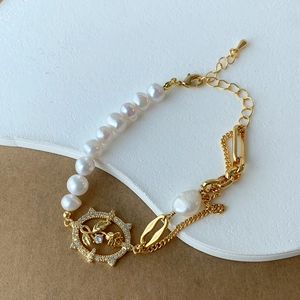 Detail of freshwater pearl bracelet with golden Cuban chain and hollow flower pendant