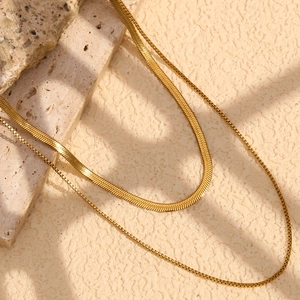 Close-up of double layer 18K gold plated snake and box chain on marble background