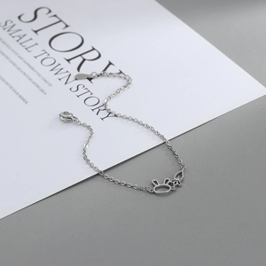 Detailed view of silver rabbit and carrot charms on a hollow-carved designer bracelet