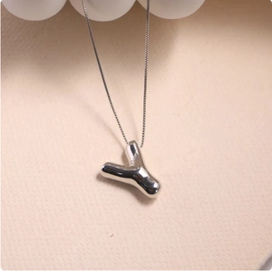 Macro detail of a 3D silver balloon letter Y pendant with mirror-polished surface