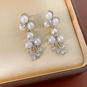 Détail de boucles d'oreilles de mariée en argent avec perles et strass brillants