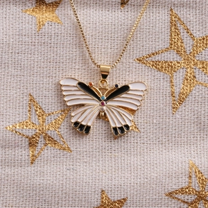 Macro shot of gold butterfly necklace pendant with black enamel and colored stones