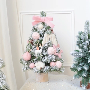 Mini pink flocked Christmas tree with wood base and decorative ornaments in a home setting