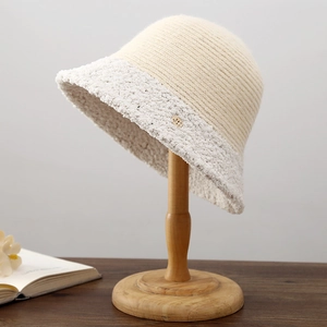 Détail d'un chapeau bob en tricot crème avec logo doré et bordure en laine bouclée