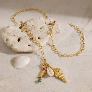 Collier marin doré avec coquillages et pendentif poisson sur surface en pierre naturelle