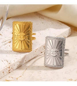 Detailed view of gold and silver rectangular LUCKY rings on a natural stone base
